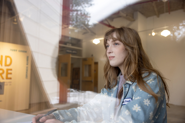 Sophie H. sitting down behind glass on the Okanagan campus