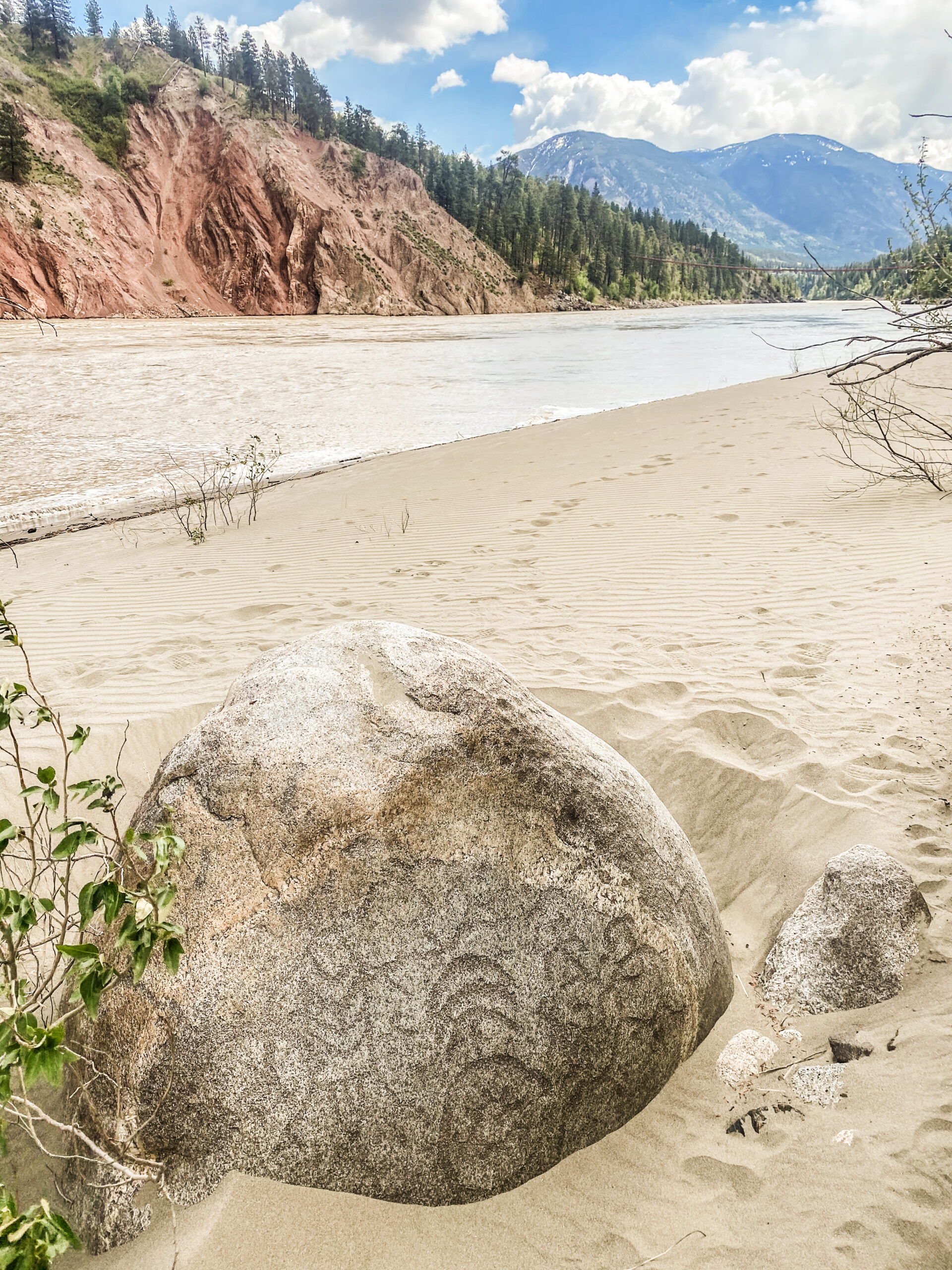 A rock in front of a river with Indigenous writing on it.