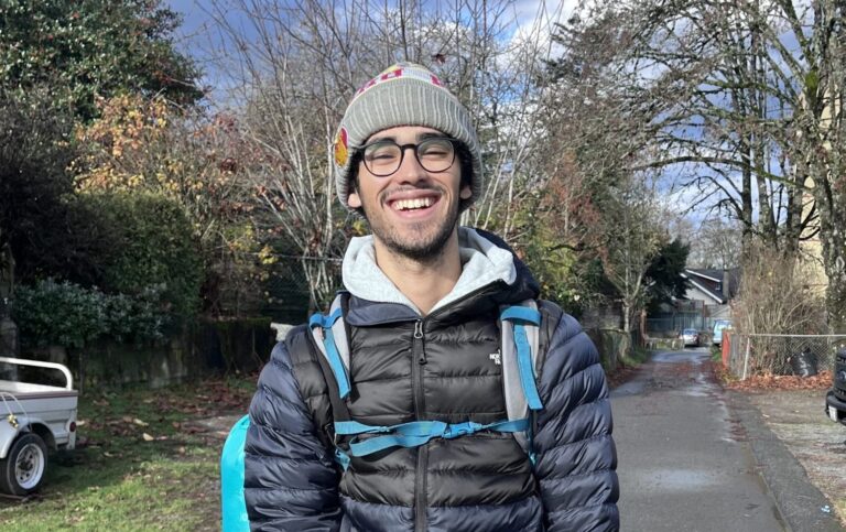 Hammad J stands in road with a pack and water bottle.