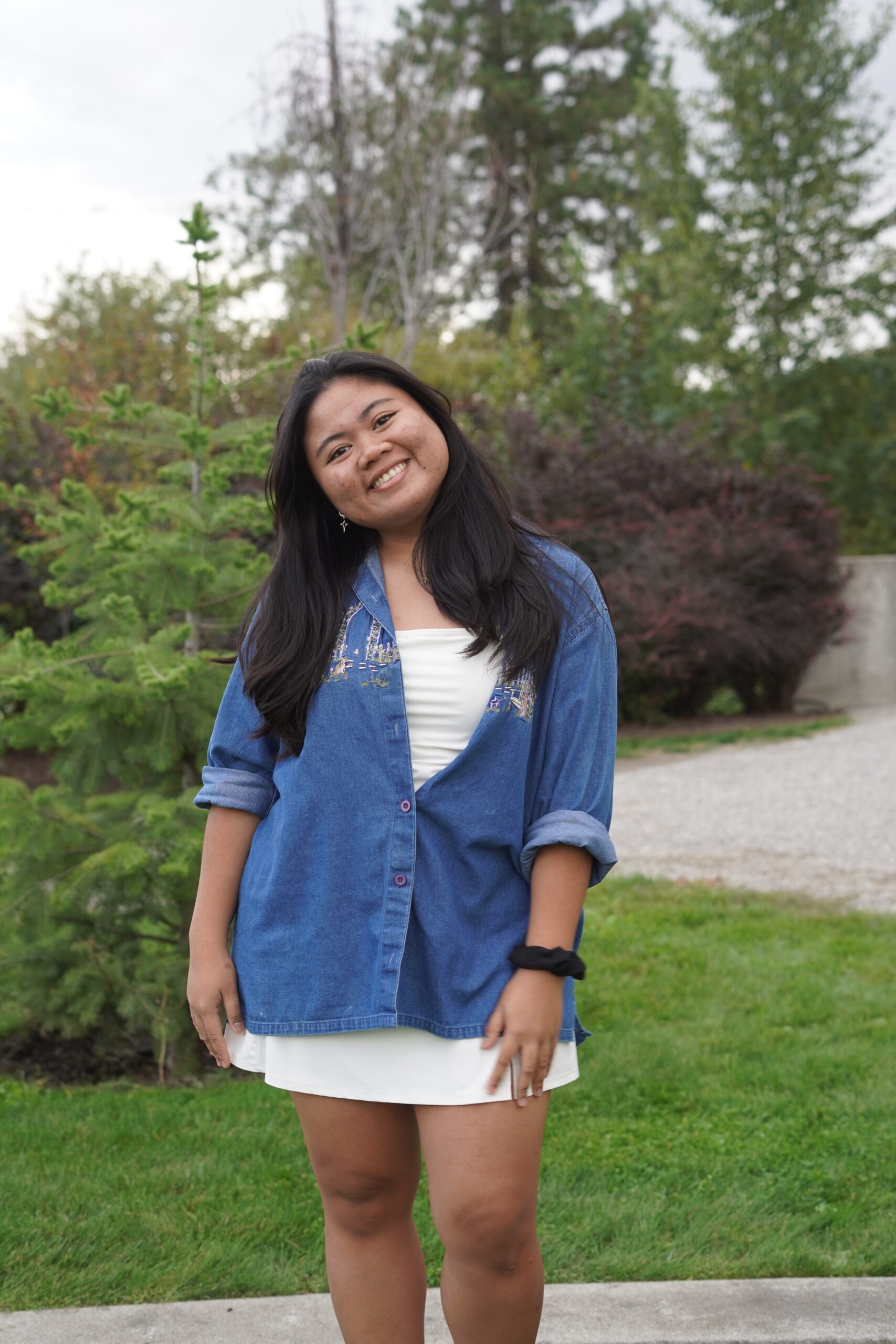 Student in a blue shirt stands in a garden.