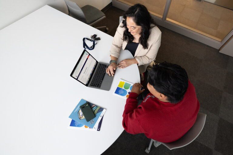 Advisor and student looking at a laptop and student guide