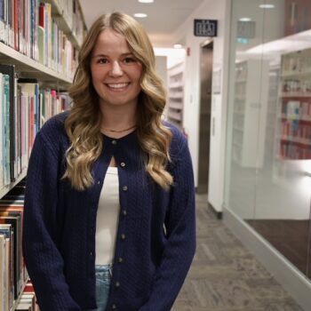 Kelsey standing in the UBC Okanagan library