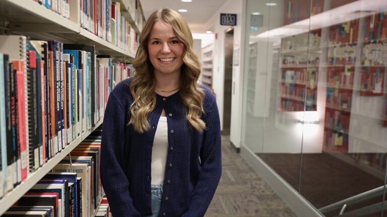 Kelsey standing in the UBC Okanagan library