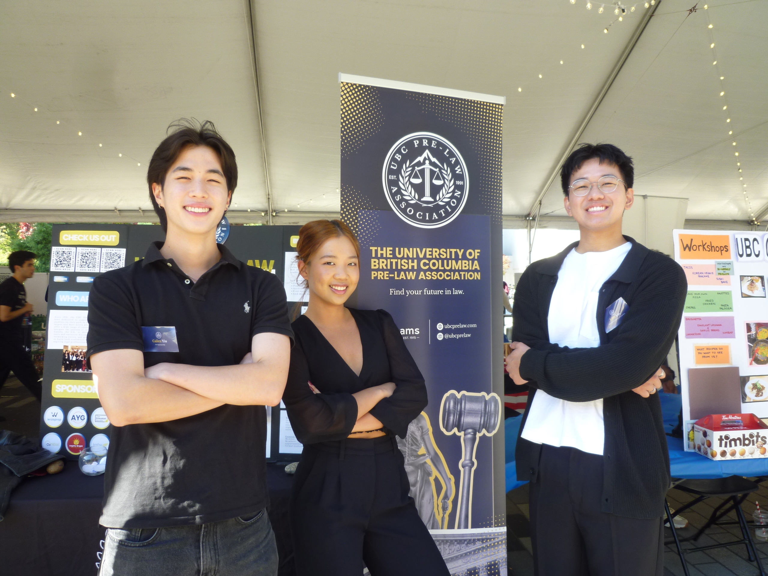 Three students standing in front of the pre-law association booth at club days.