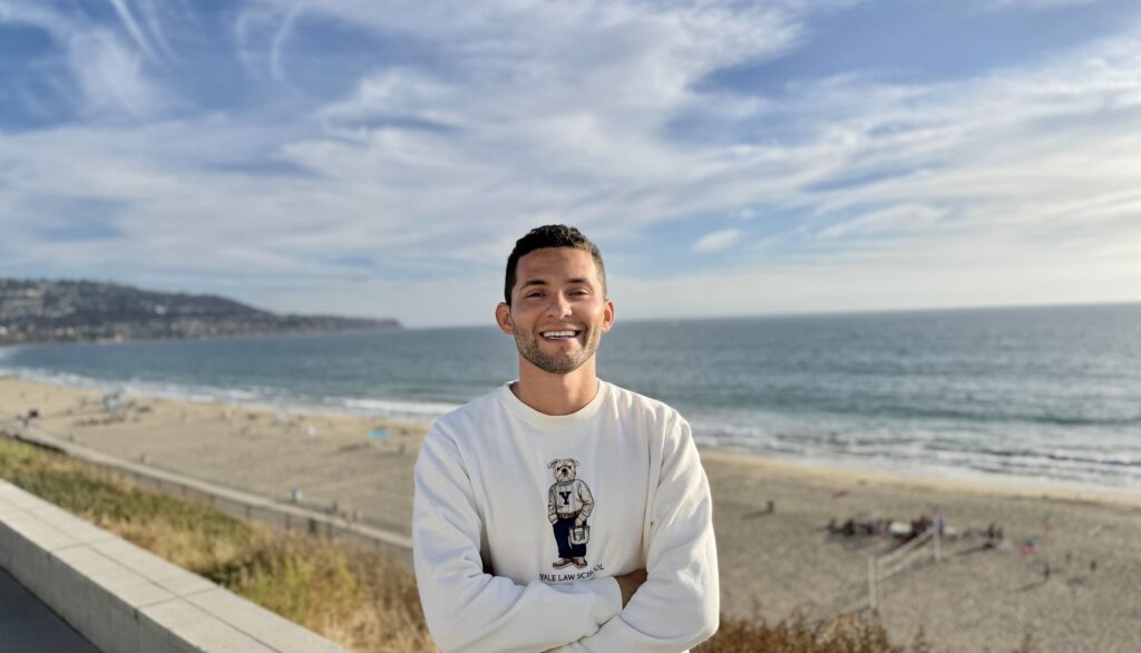 Danilo on a beach wearing a Yale Law School tshirt